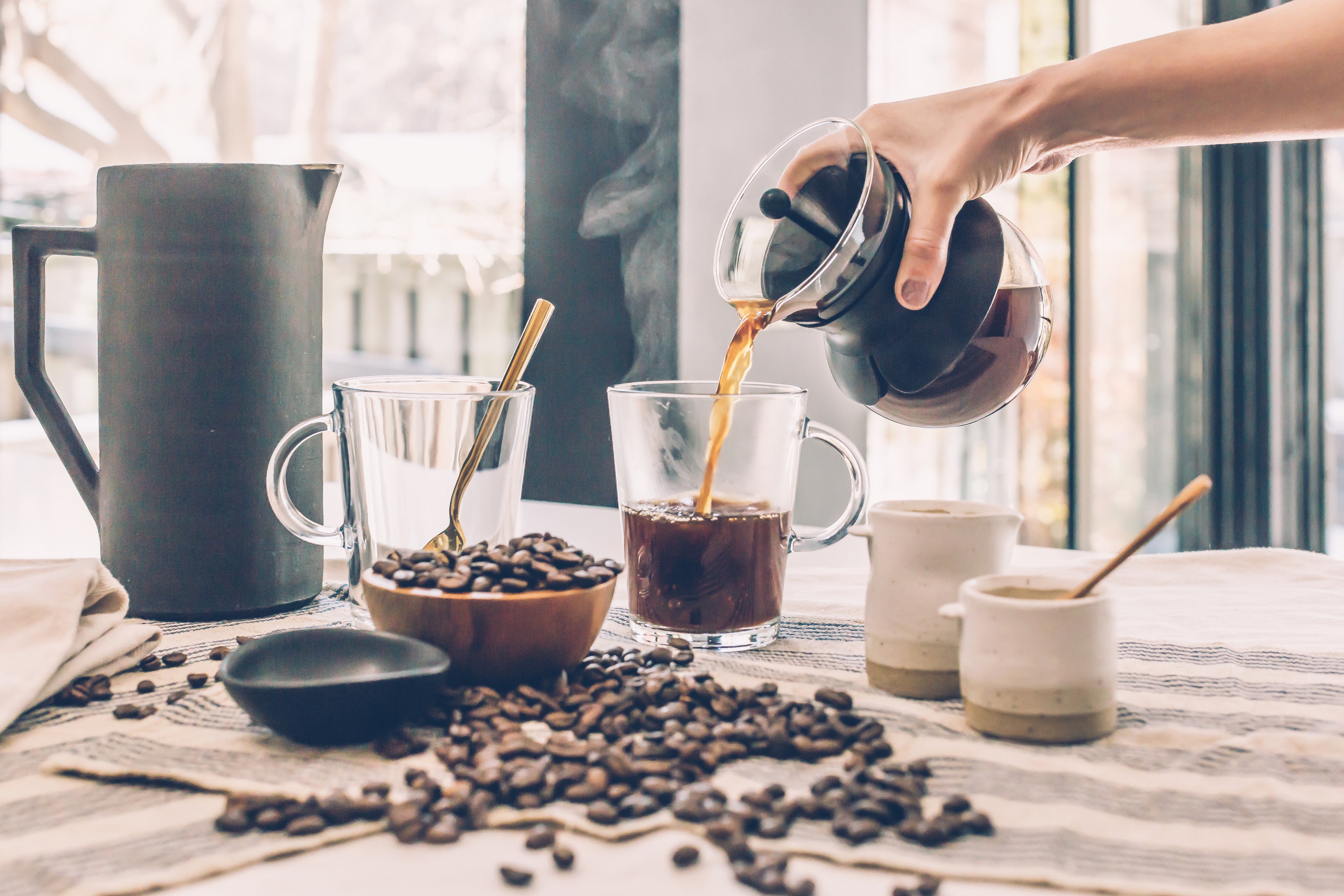 A man is filling a cup of coffee to drink