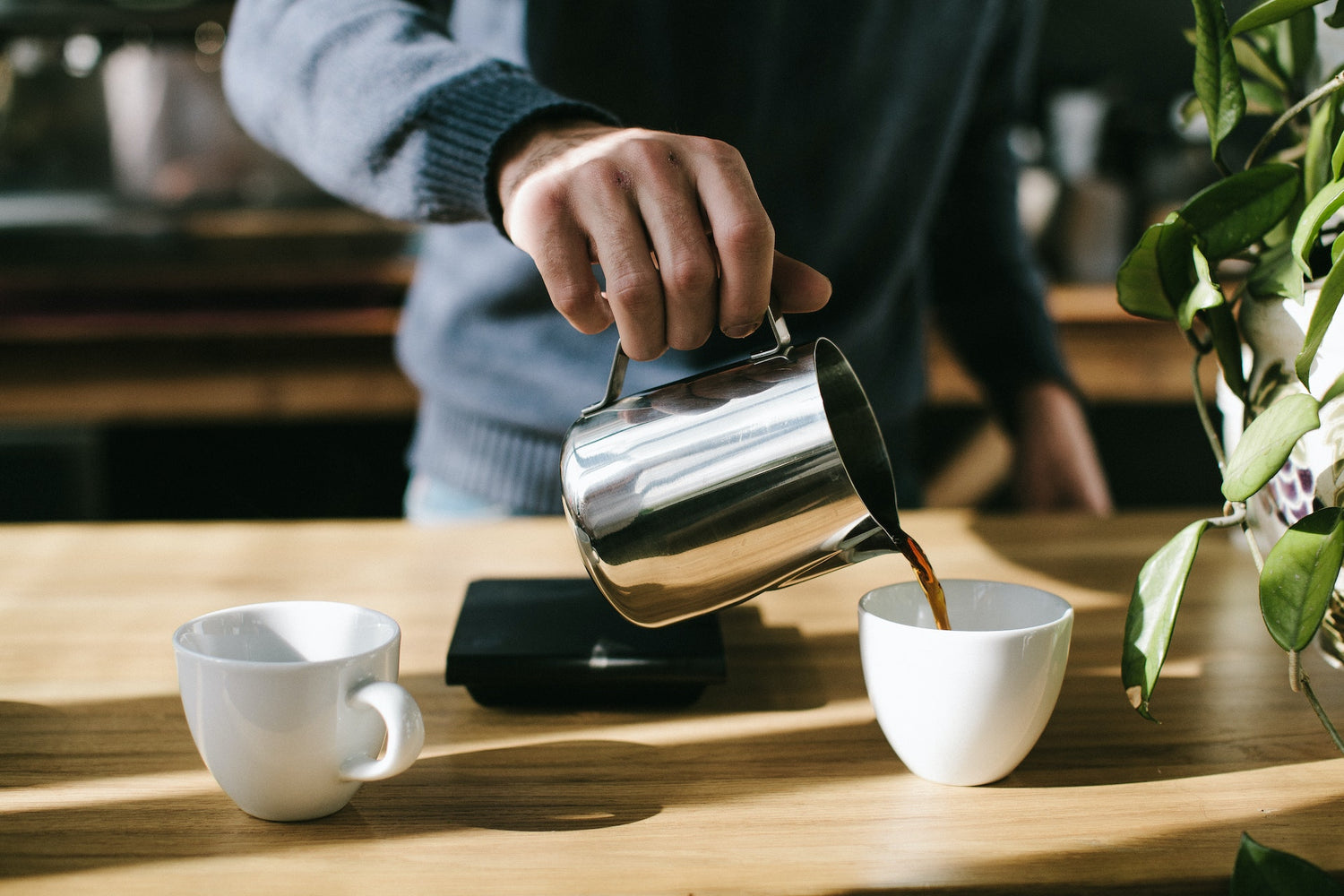 A man is filling a cup with coffee and making it ready to drink