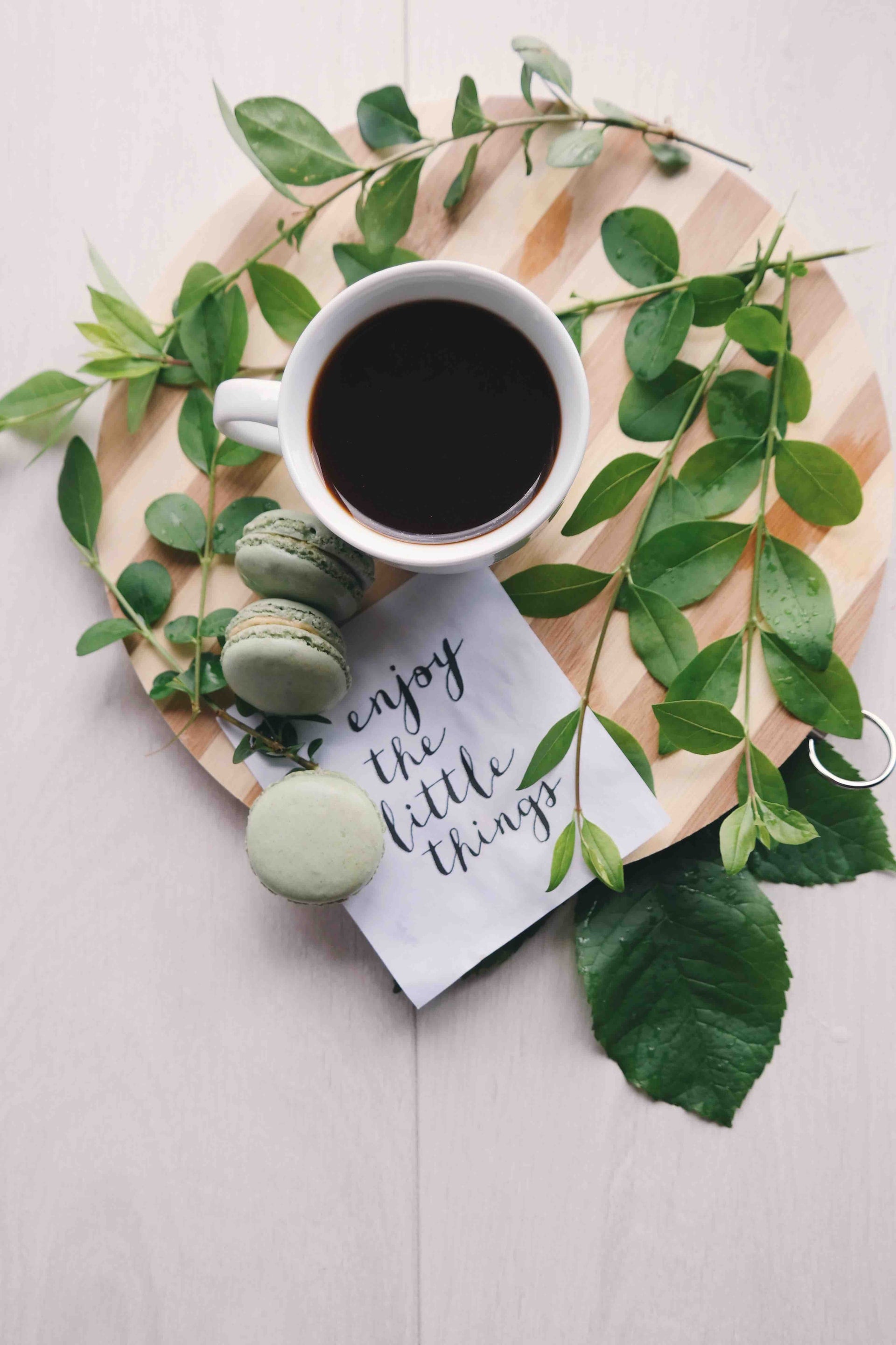 A cup of black tea with a note  written as "enjoy the little things" 